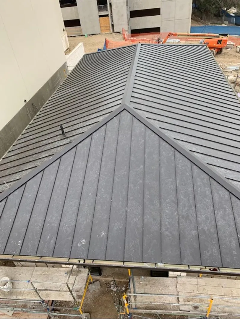 Commercial metal roof construction with crane equipment in Parkland